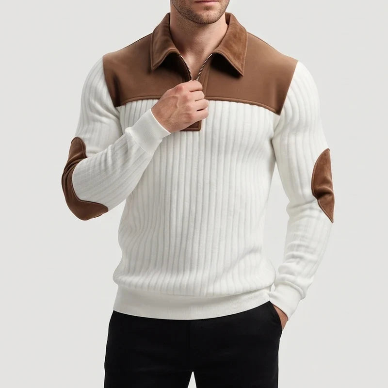 Man wearing a white ribbed knit quarter-zip jumper with a brown collar and elbow patches, partially zipped.