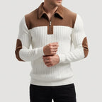 Man wearing a white ribbed quarter-zip jumper with brown collar, shoulder panels, and elbow patches, posing with hands clasped.