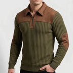 Man wearing a green ribbed knit quarter-zip jumper with brown collar, shoulder, and elbow patches, posing with a hand in his pocket.