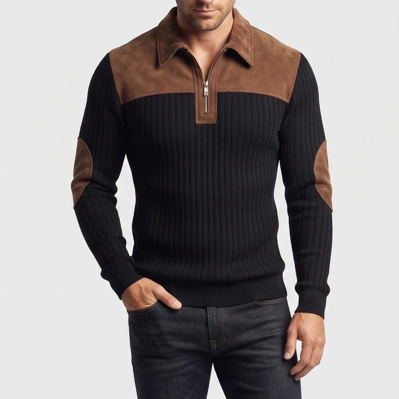 Man wearing a black ribbed knit quarter-zip jumper with brown suede collar, shoulder panels, and elbow patches, posing with hand in pocket.