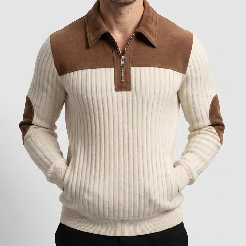 Man wearing a cream ribbed quarter-zip jumper with a brown suede collar, shoulder panel, and elbow patches, hands in pockets.
