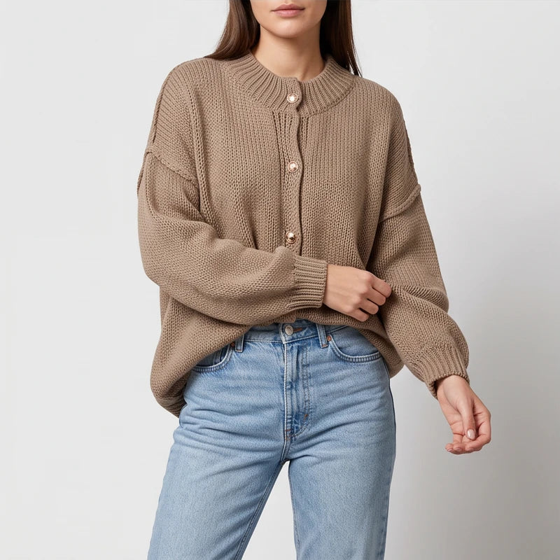 Woman wearing a light brown knit cardigan with golden buttons, an oversized fit, and light wash jeans.