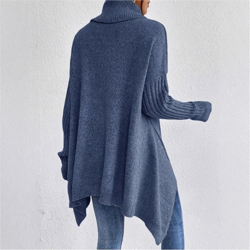 Person seen from behind wearing a loose-fitting blue knit turtleneck sweater with ribbed cuffs and an asymmetrical hem.