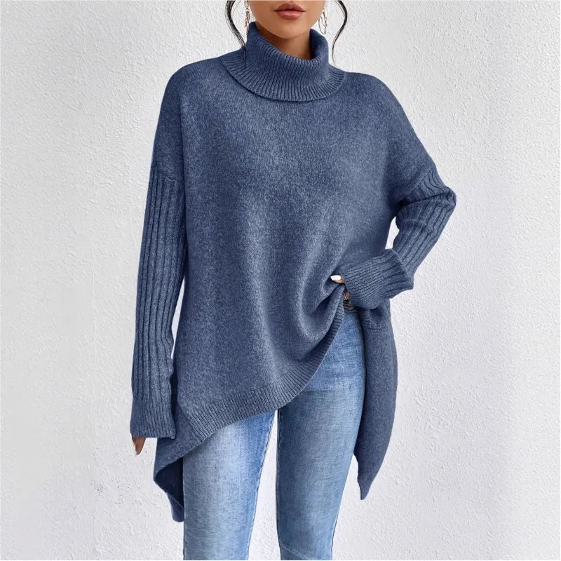 Woman wearing a mottled blue knit turtleneck sweater with ribbed cuffs and an asymmetrical high-low hem over jeans.