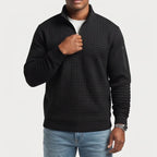Man wearing a black quarter-zip waffle knit jumper with a chest pocket and arm pocket, pulling the zipper.