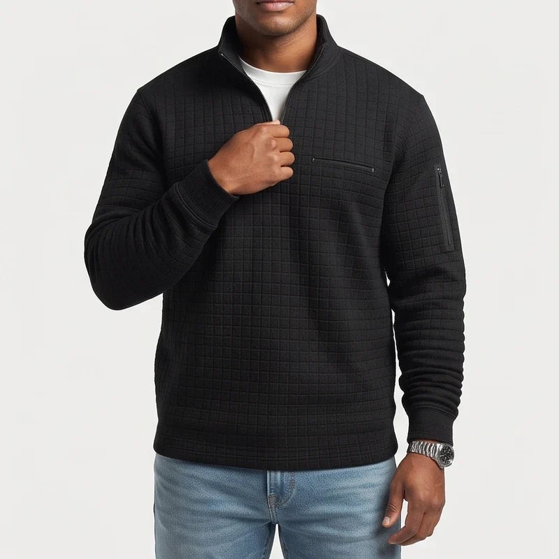 Man wearing a black quarter-zip waffle knit jumper with a chest pocket and arm pocket, pulling the zipper.