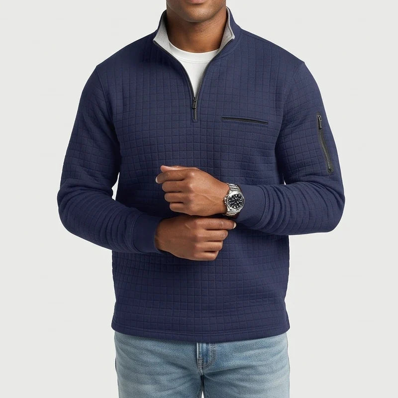Man wearing a navy blue quilted quarter-zip pullover with a chest pocket and arm zipper, adjusting a silver watch.