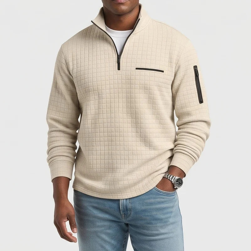 Man wearing a light beige waffle knit quarter-zip jumper with a black zipper and a zippered pocket on the sleeve.