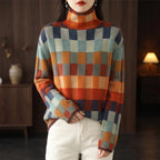 Woman wearing a high-neck sweater with a colorful checkered pattern in shades of orange, blue, green, and gray.