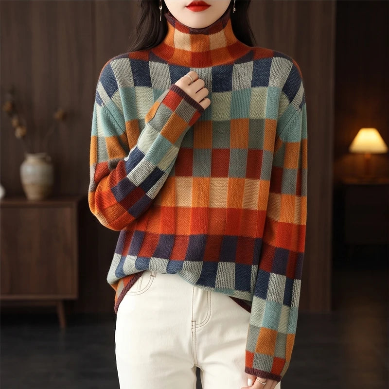 Woman wearing a colorful checkered turtleneck sweater in shades of orange, blue, and green with cream pants.