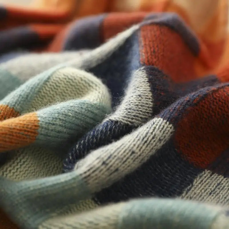 Close-up of a soft, textured knit fabric with a multicolored checked pattern in rust, navy, teal, and grey.