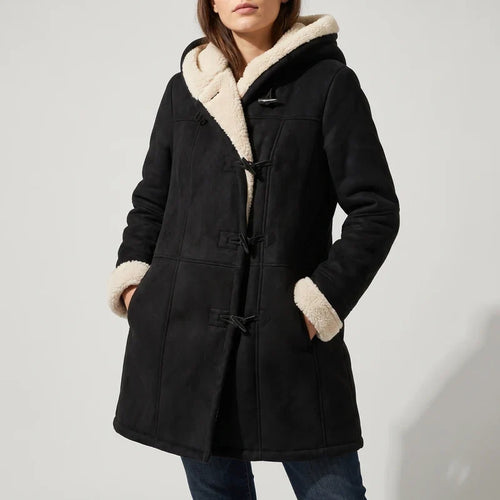Woman wearing a black suede-look duffle coat with creamy borg lining, toggle closures, and hands in pockets.