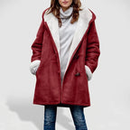Woman wearing an open red suede coat with a white borg lining and toggle closures, over a gray turtleneck sweater and jeans.