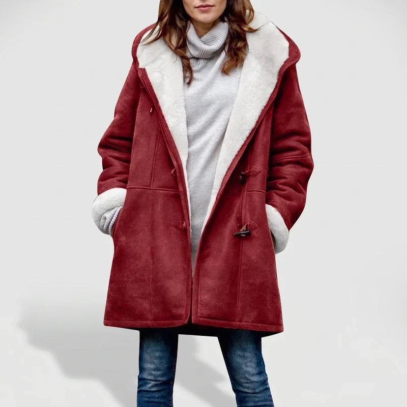 Woman wearing an open red suede coat with a white borg lining and toggle closures, over a gray turtleneck sweater and jeans.