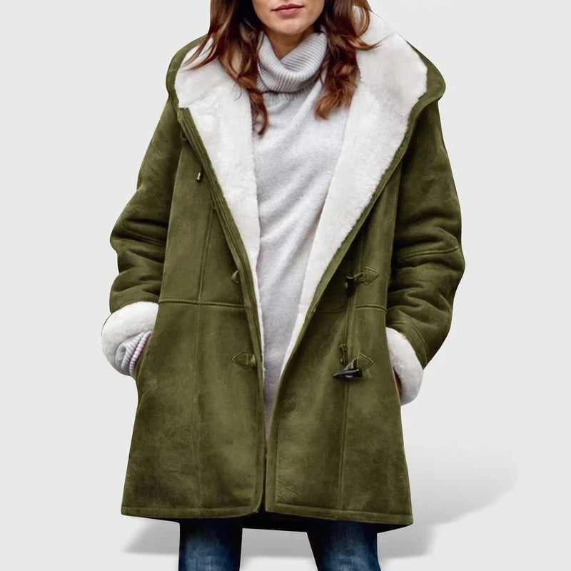 Woman wearing an olive green hooded coat with white borg lining and dark toggle closures, over a gray turtleneck.