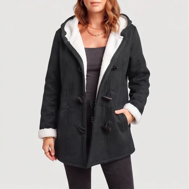 Woman wearing an open black hooded coat with white borg lining, toggle closures, and her hand in a pocket.