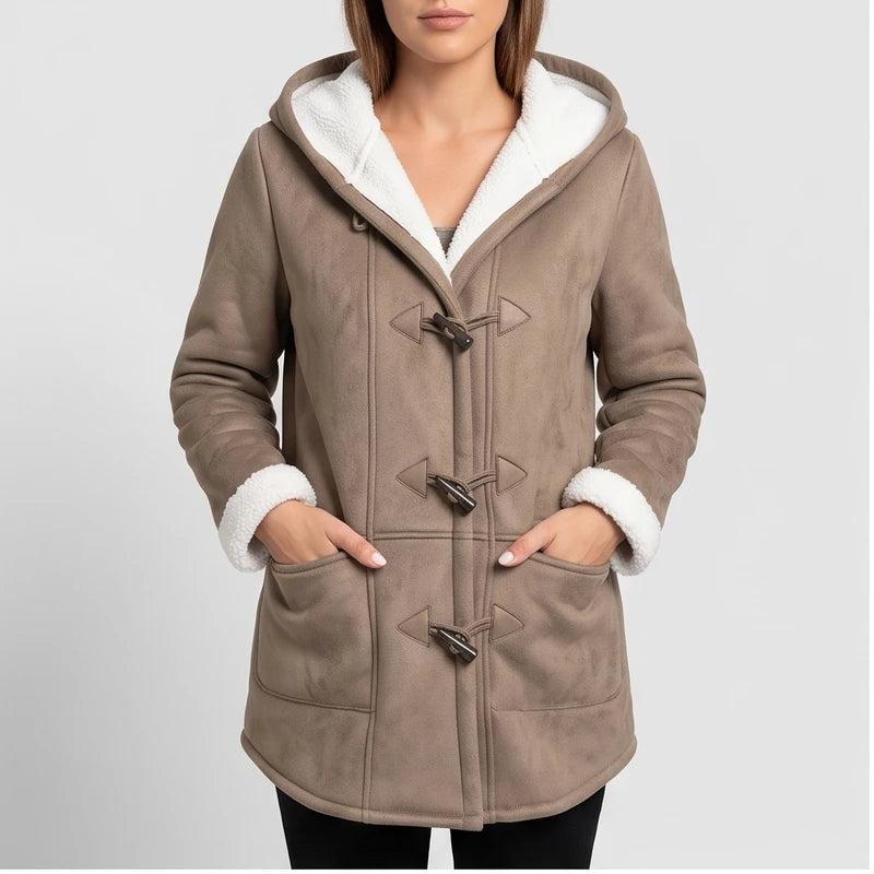 Woman wearing a taupe hooded coat with white borg lining and dark toggle closures, hands in front pockets.