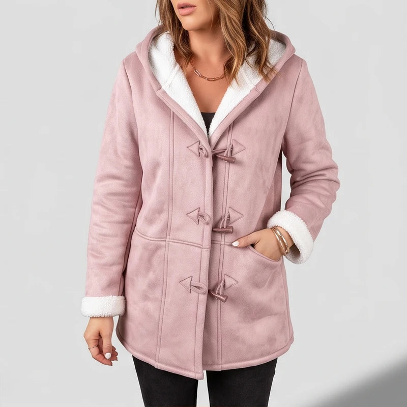 Woman wearing a pink suede-like hooded coat with white borg lining, toggles, and front pockets, against a light background.