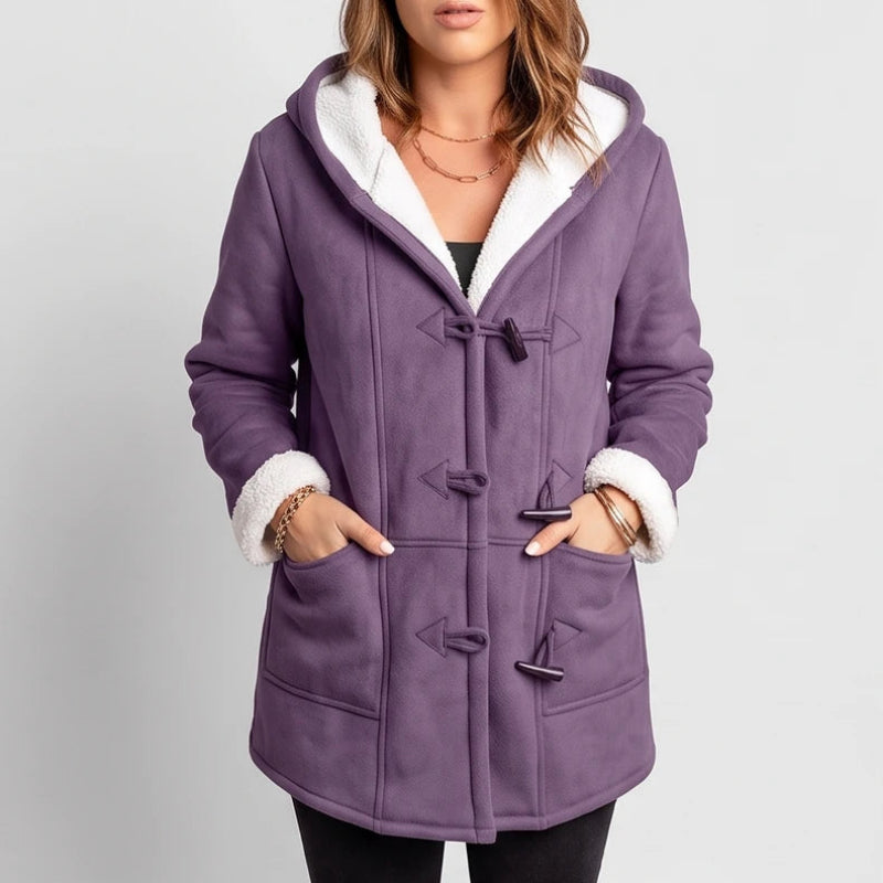 Woman wearing a mid-length purple hooded coat with white borg lining and three toggle closures.