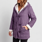 Woman wearing a purple faux suede hooded jacket with white borg lining and dark toggle closures, hand in pocket.