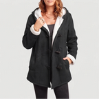 Woman wearing an open black hooded coat with white borg lining and toggles, one hand in pocket.