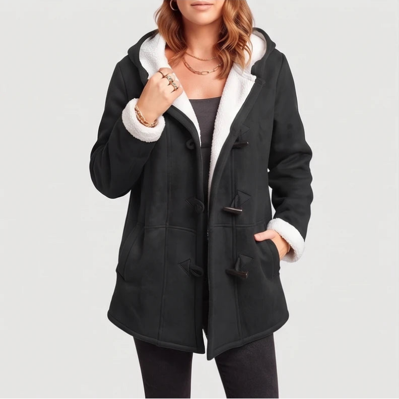 Woman wearing an open black hooded coat with white borg lining and toggles, one hand in pocket.