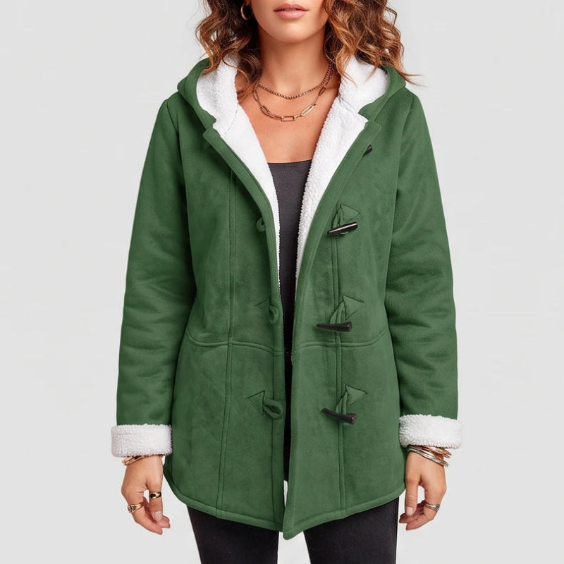 Woman wearing a green suede-like hooded coat with white sherpa lining, black toggle closures, and cuffs rolled up.