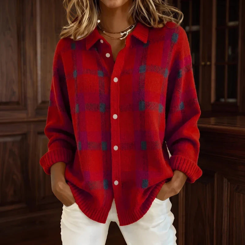 Woman wearing a red knit cardigan with a black and magenta plaid pattern, white buttons, and white pants.