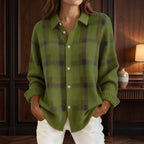 Woman wearing a fuzzy olive green knit cardigan with dark plaid pattern, white buttons, and white pants.
