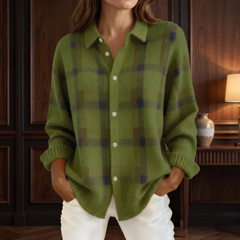 Woman wearing a fuzzy olive green knit cardigan with dark plaid pattern, white buttons, and white pants.