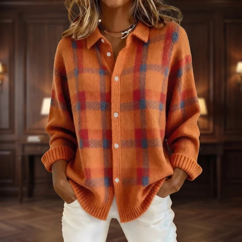 Woman wearing an orange knit cardigan with a red and blue plaid pattern, white buttons, and ribbed cuffs.