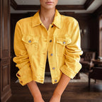 Woman wearing a vibrant yellow cropped denim jacket with silver buttons and chest pockets, posed indoors.