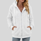 Woman wearing a white fluffy full-zip hoodie with white drawstrings, hands in the front pockets.