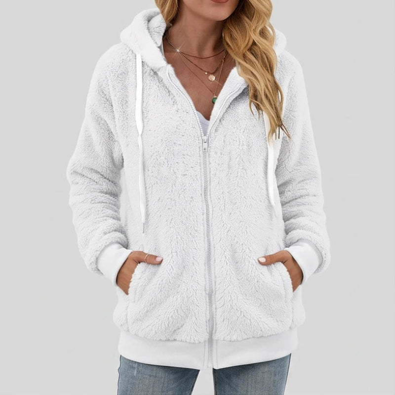 Woman wearing a white fluffy full-zip hoodie with white drawstrings, hands in the front pockets.