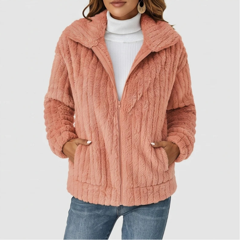 Woman wearing a fuzzy peach-colored fleece zip-up jacket over a white turtleneck, hands in pockets.