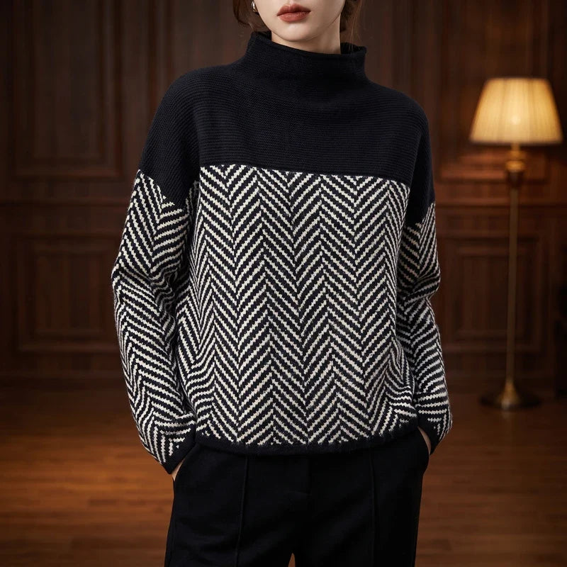 Woman wearing a black and white herringbone pattern jumper with a solid black roll neck and dark trousers.