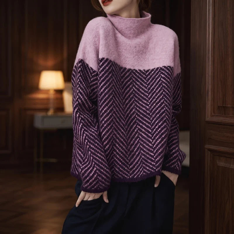 Woman wearing a cozy, pink and purple color-block jumper with a herringbone pattern, hands in navy pants pockets.