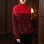 Woman wearing a red and black color block jumper with a distinct herringbone pattern and a high neckline.