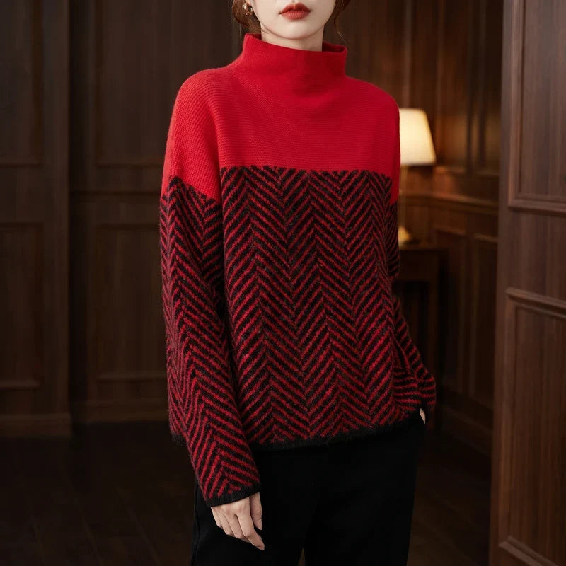 Woman wearing a red and black color block jumper with a distinct herringbone pattern and a high neckline.