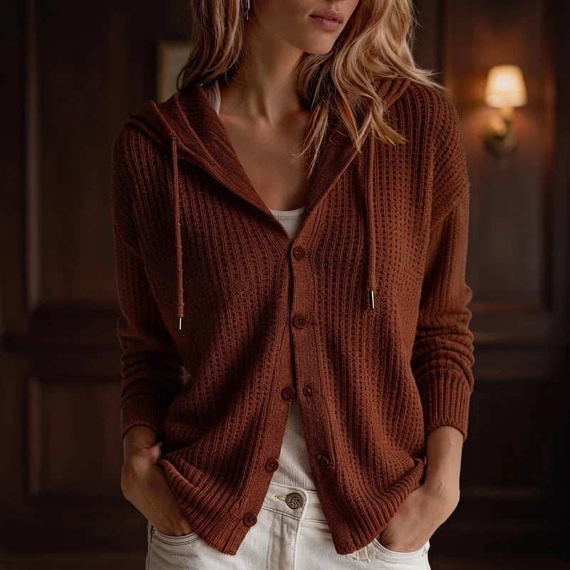 Woman wearing an open, rusty brown knit hooded cardigan with five buttons over a white top and light jeans.