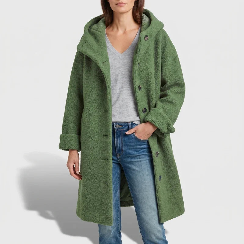 Woman wearing a long, textured green hooded coat over a gray V-neck tee and blue jeans.