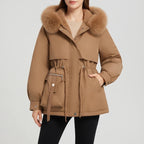 Woman wearing a warm brown parka with a fluffy faux fur-trimmed hood, cinched waist, and zippered pocket.