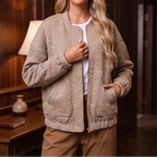 Woman wearing a beige quilted bomber jacket with a floral pattern, ribbed cuffs, zipper, and front pockets.