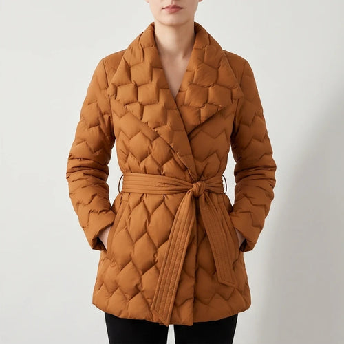 Woman wearing a rust-colored quilted puffer coat with a wide collar, tied at the waist, hands in pockets.