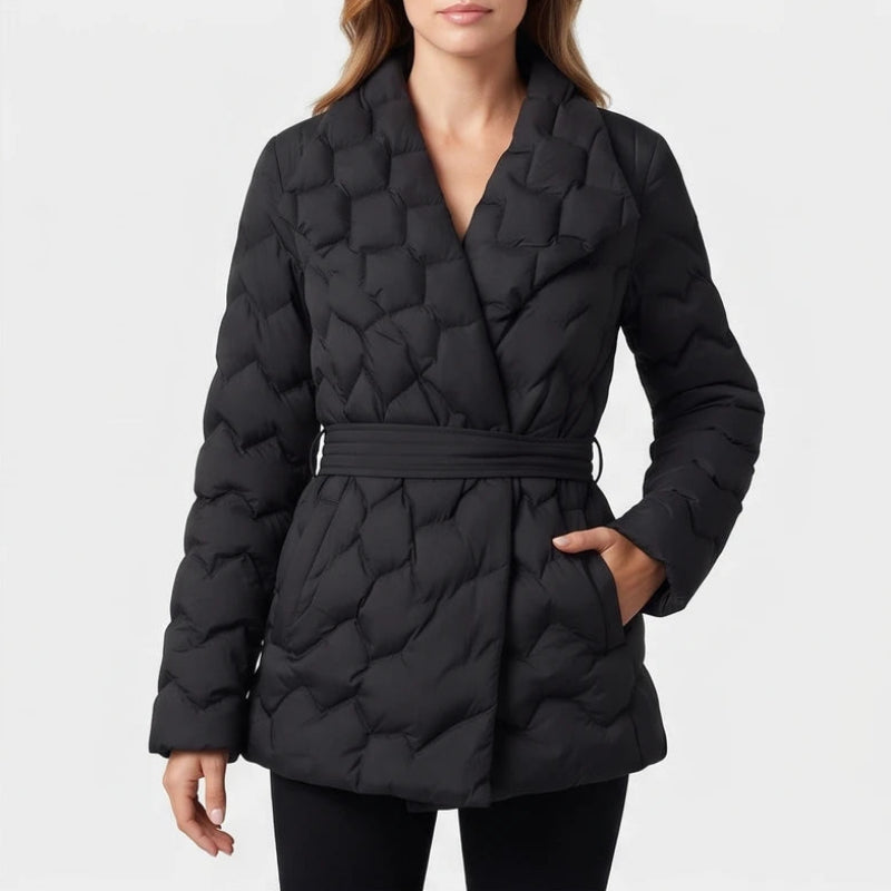 Woman wearing a black quilted puffer coat with a wide lapel collar and a belted waist, standing against a white background.