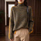 Woman wearing a mottled dark olive and yellow knit roll neck jumper with yellow stripes on the sleeves.