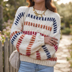 Woman wearing a cream chunky knit jumper with red, orange, and navy textured stripes over light blue jeans.