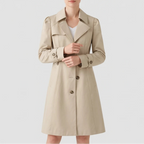 Woman wearing a beige trench coat with a wide collar, shoulder epaulets, double-breasted buttons, and cinched cuffs.