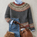 Flat lay of a grey knit jumper with a rustic Fair Isle pattern, layered over a blue striped shirt and jeans.