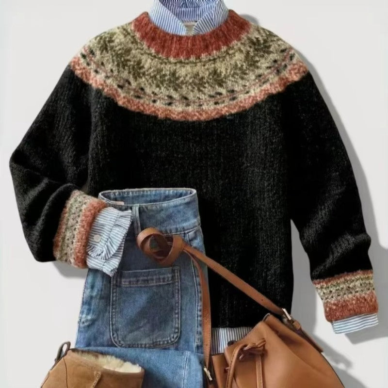 Flat lay of a black knit sweater with a rust, green, and cream Fair Isle yoke, styled over a striped shirt with jeans and a brown bag.